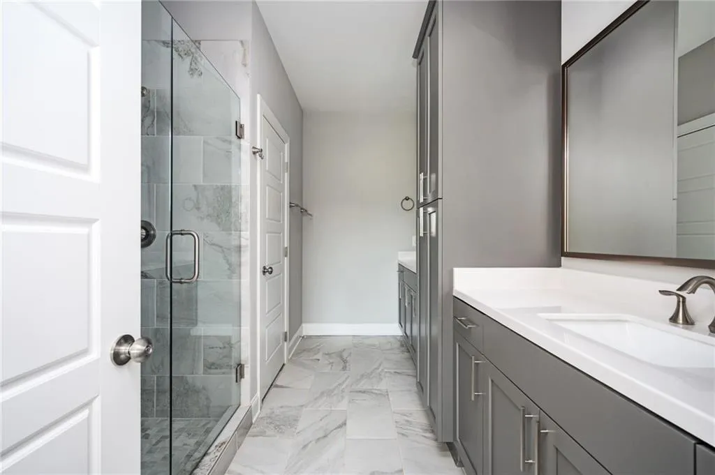 Full bath with marble finish flooring, vanity, a shower stall, and baseboards
