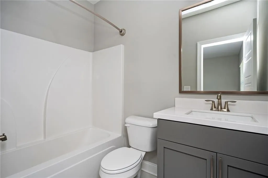 Bathroom with vanity, toilet, shower / bath combination, and baseboards