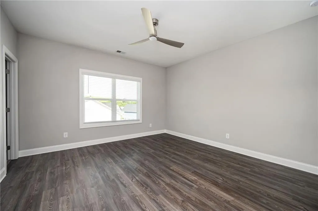 Spare room featuring dark wood-style floors, baseboards, and ceiling fan