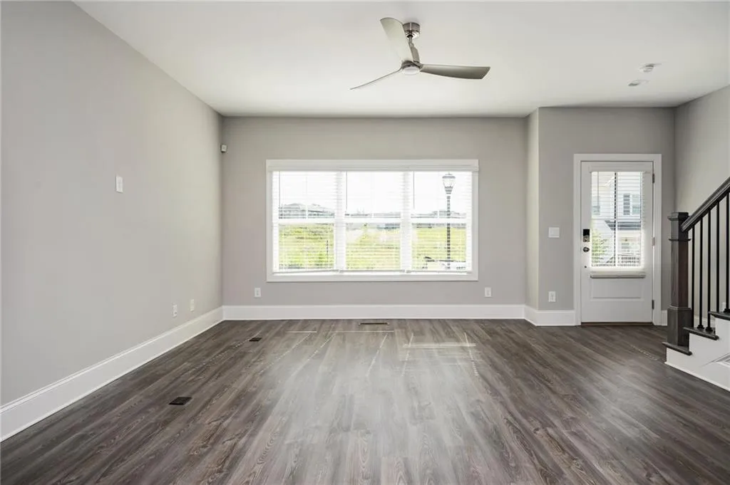 Unfurnished living room with stairs, dark wood-style flooring, and baseboards
