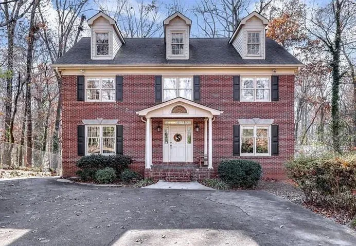 Brick two-story colonial-style residence featuring a prominent gabled entry portico