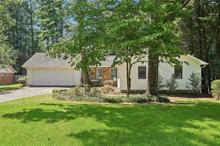 Charming single-story home nestled on a tree-lined lot with mature landscaping and expansive lawn