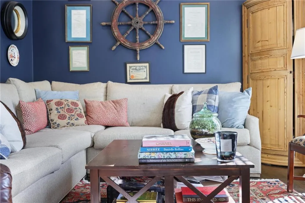 Rich blue wall finish, wood-finish flooring, corner cabinet with paneled doors, and a wood coffee table with X-detail sides