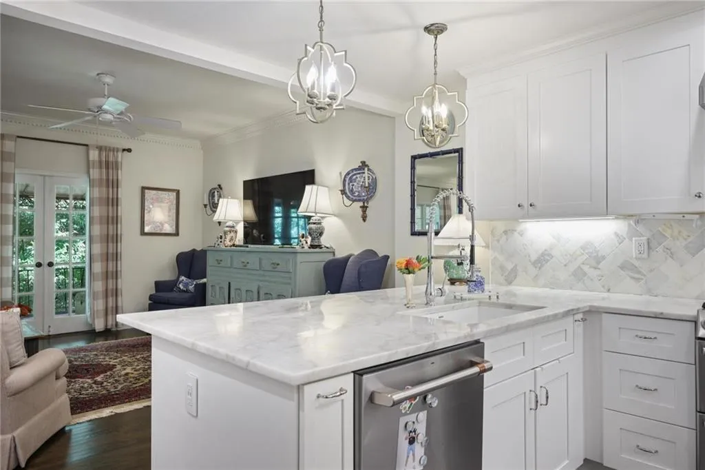 Kitchen featuring white cabinetry, a built-in stainless steel dishwasher, a single basin sink with a gooseneck faucet, and a light-toned countertop