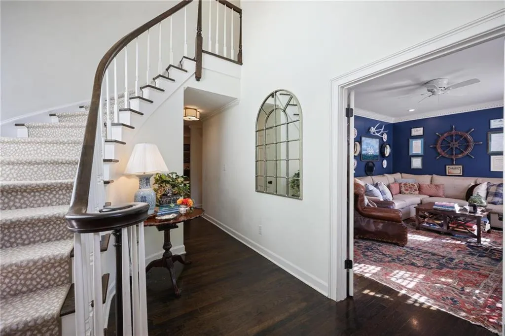 Curved staircase with dark wood handrail, white balusters, and patterned runner