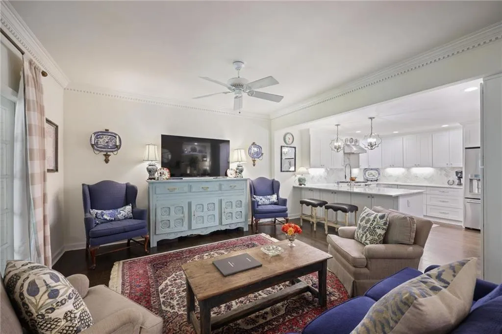 Open-concept living area with dark wood-finish flooring, crown molding, and a ceiling fan