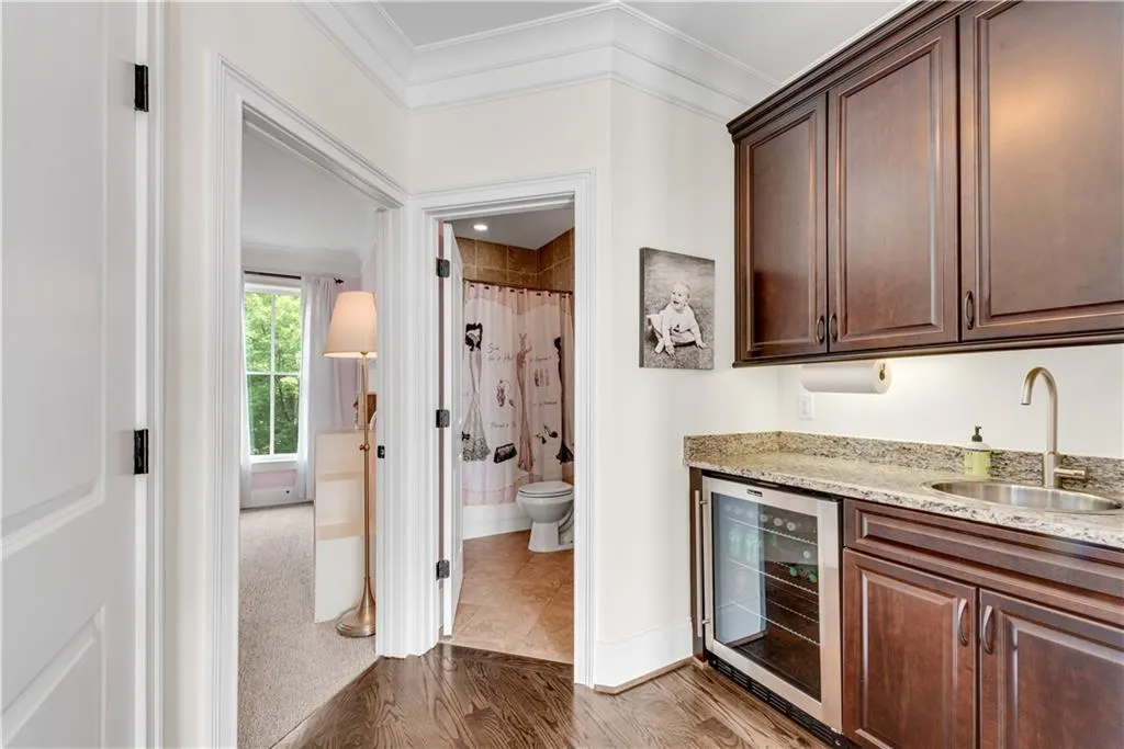 Kitchen featuring ornamental molding, wood-type flooring, sink, and beverage cooler