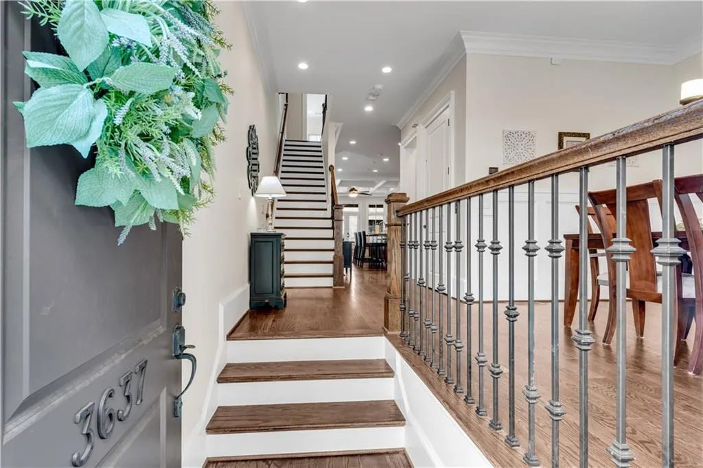 Stairway with ornamental molding, hardwood / wood-style floors, and ceiling fan