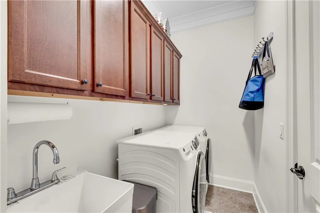 Laundry area featuring independent washer and dryer, ornamental molding, sink, and cabinets
