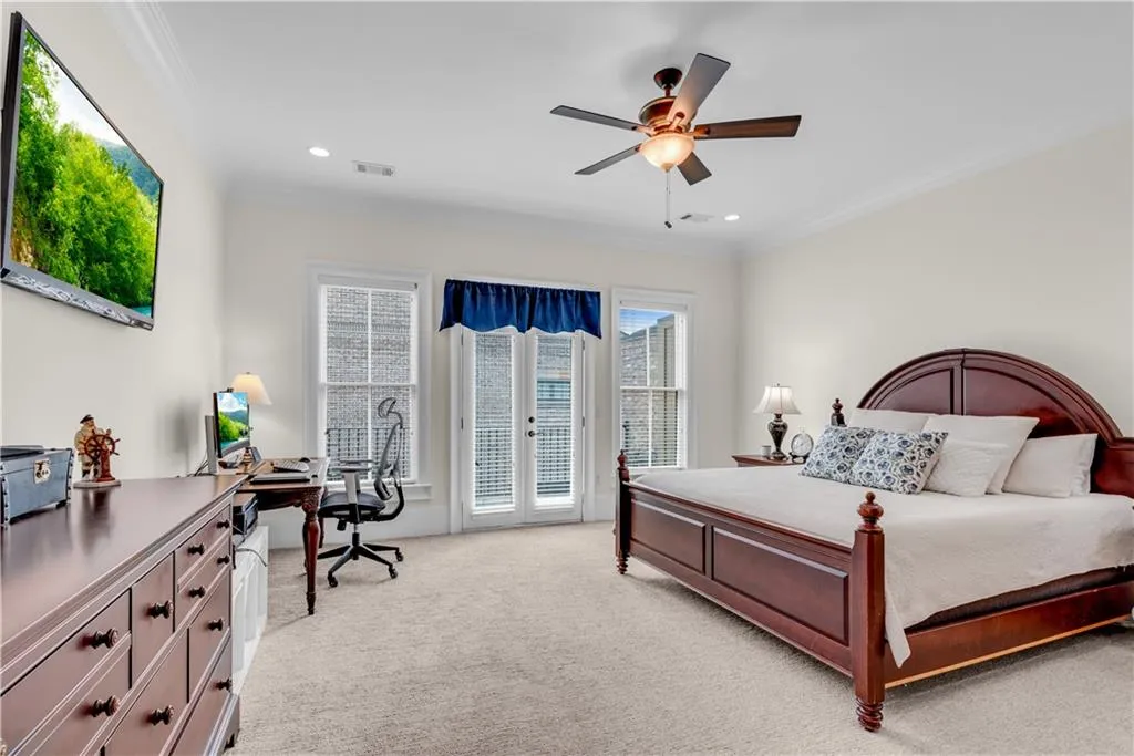 Carpeted bedroom featuring ornamental molding, access to exterior, and ceiling fan