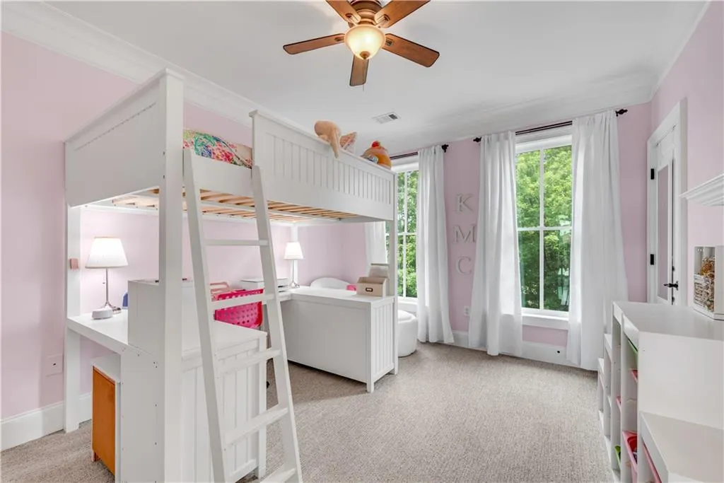 Carpeted bedroom featuring ceiling fan and crown molding