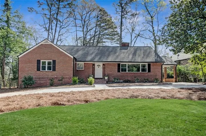 Ranch-style house with a front yard, brick siding, a chimney, a porch, and roof with shingles