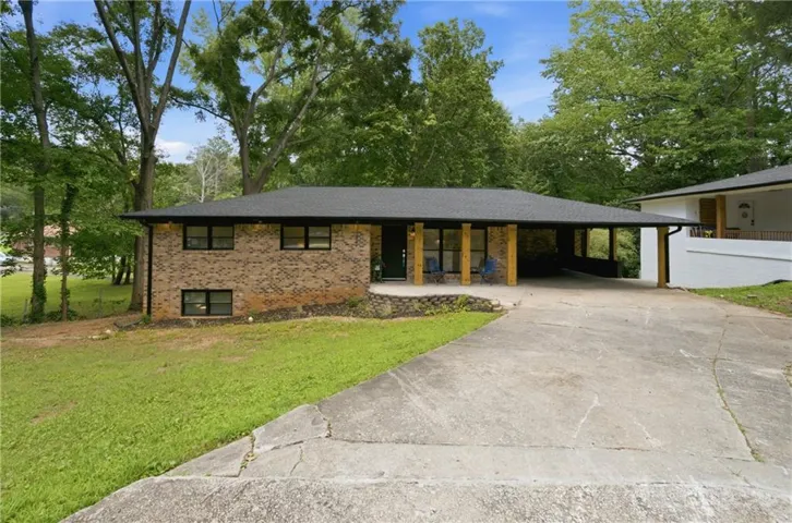 Brick exterior residence featuring a carport and mature trees