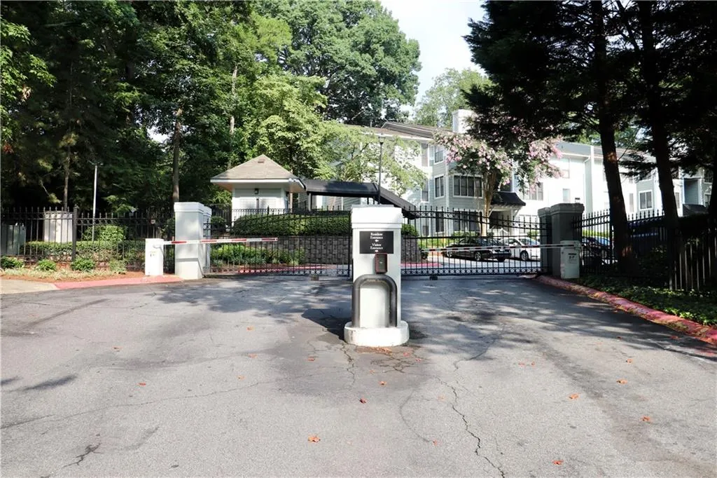View of asphalt street featuring a gate, curbs, and a gated entry