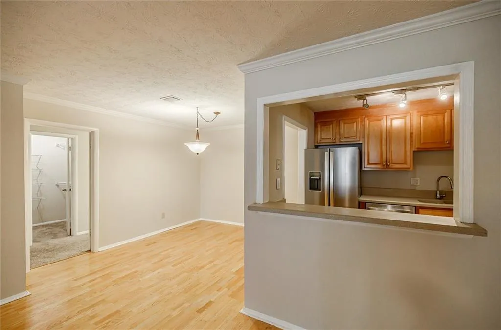 Kitchen featuring ornamental molding, appliances with stainless steel finishes, light wood-style flooring, hanging light fixtures, and light countertops
