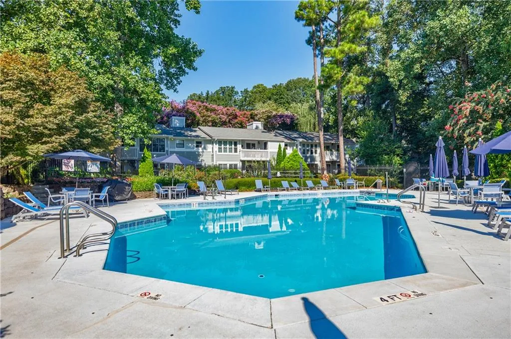Community pool featuring a patio and view of wooded area