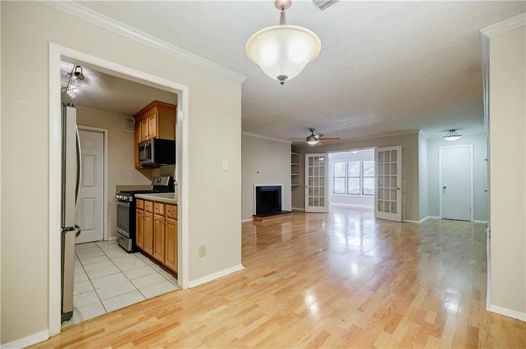 Unfurnished living room with ornamental molding, a fireplace with raised hearth, light wood finished floors, built in shelves, and a ceiling fan