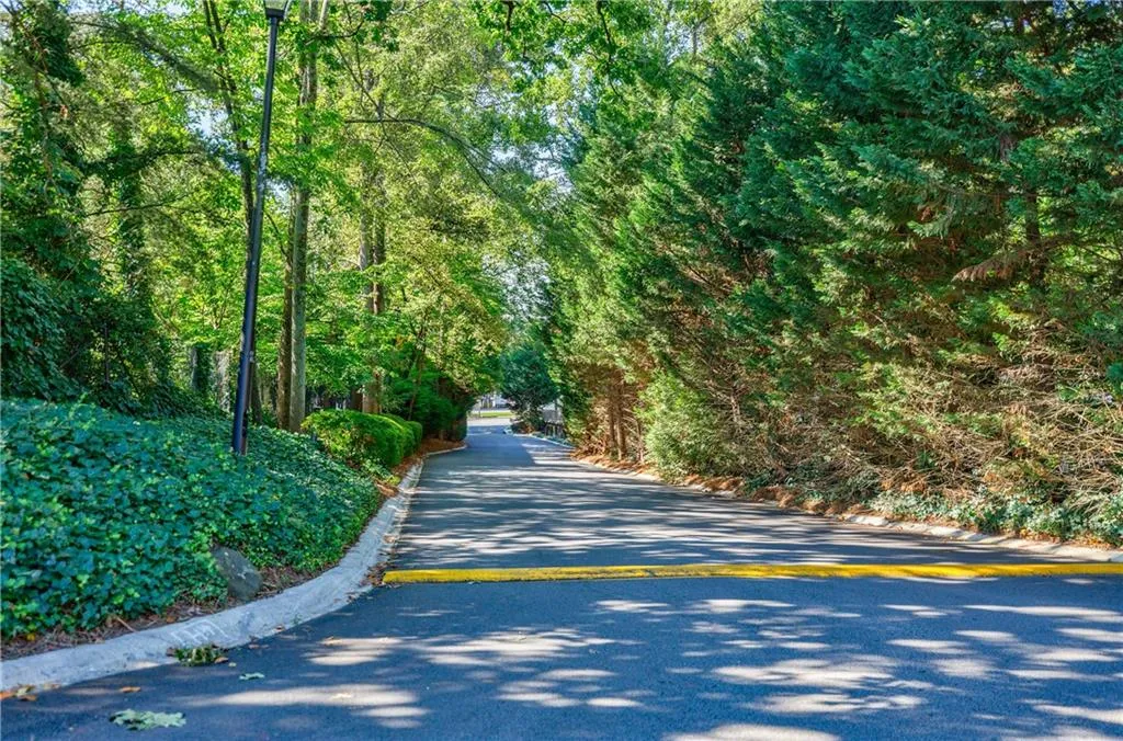 View of asphalt road featuring curbs and a view of trees
