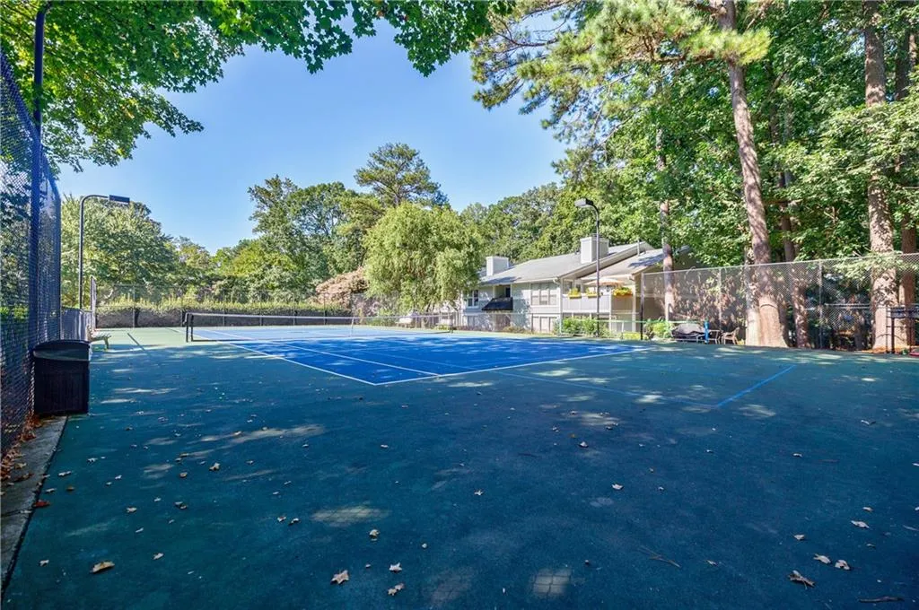 View of tennis court featuring view of scattered trees