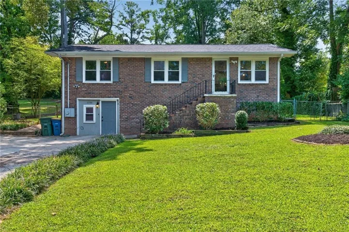 Brick exterior, front lawn, established landscaping, driveway, and an exterior entry door