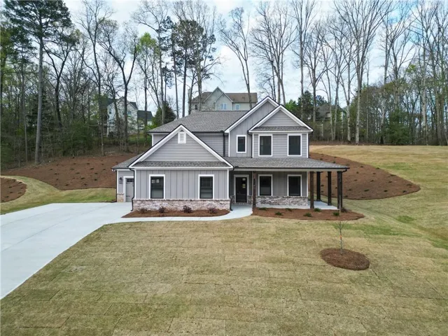 Craftsman inspired home with covered porch, a front yard, and stone siding