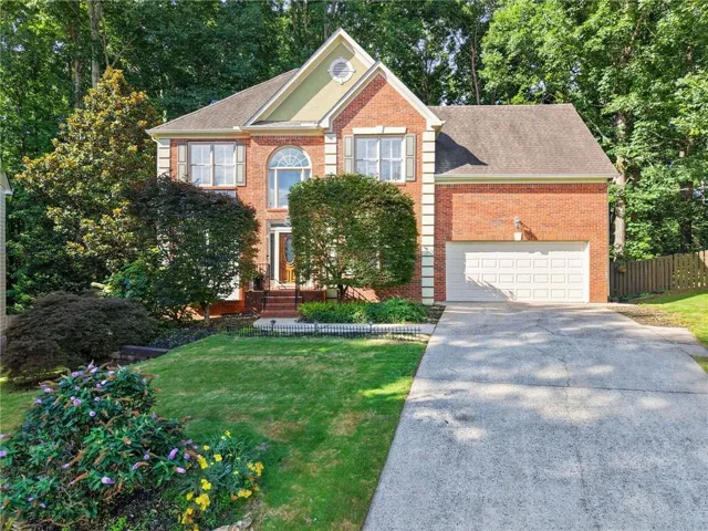 Traditional brick exterior featuring a multi-story design and an attached two-car garage