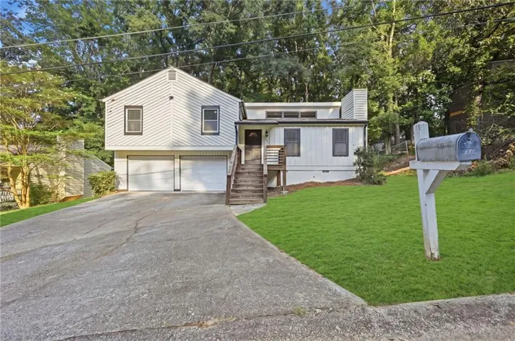White horizontal siding exterior with a two-car garage, front stairs, and mature trees