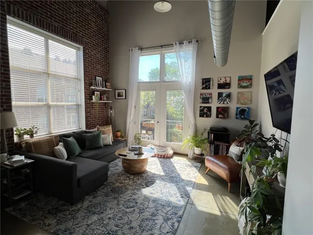 Living area featuring a tall exposed brick wall with industrial-style ductwork, concrete flooring, and high ceilings