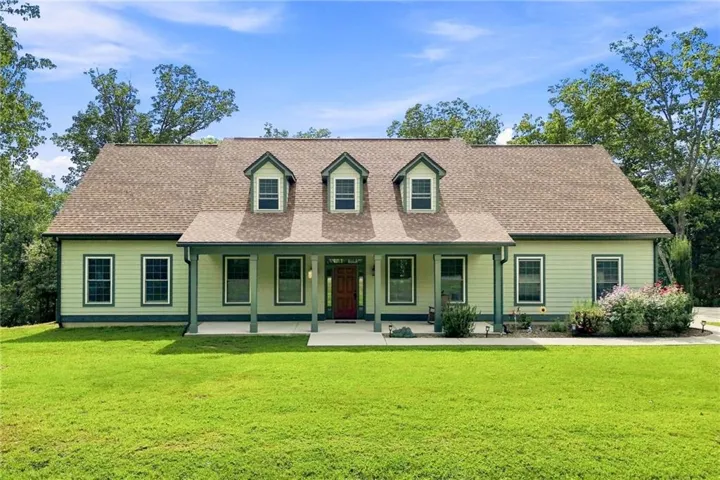Classic residence featuring a welcoming covered front porch with columns, and three dormer windows with set into a pitched roof