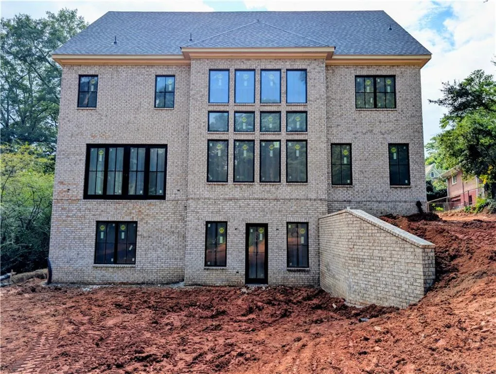 Back of property featuring brick siding and roof with shingles