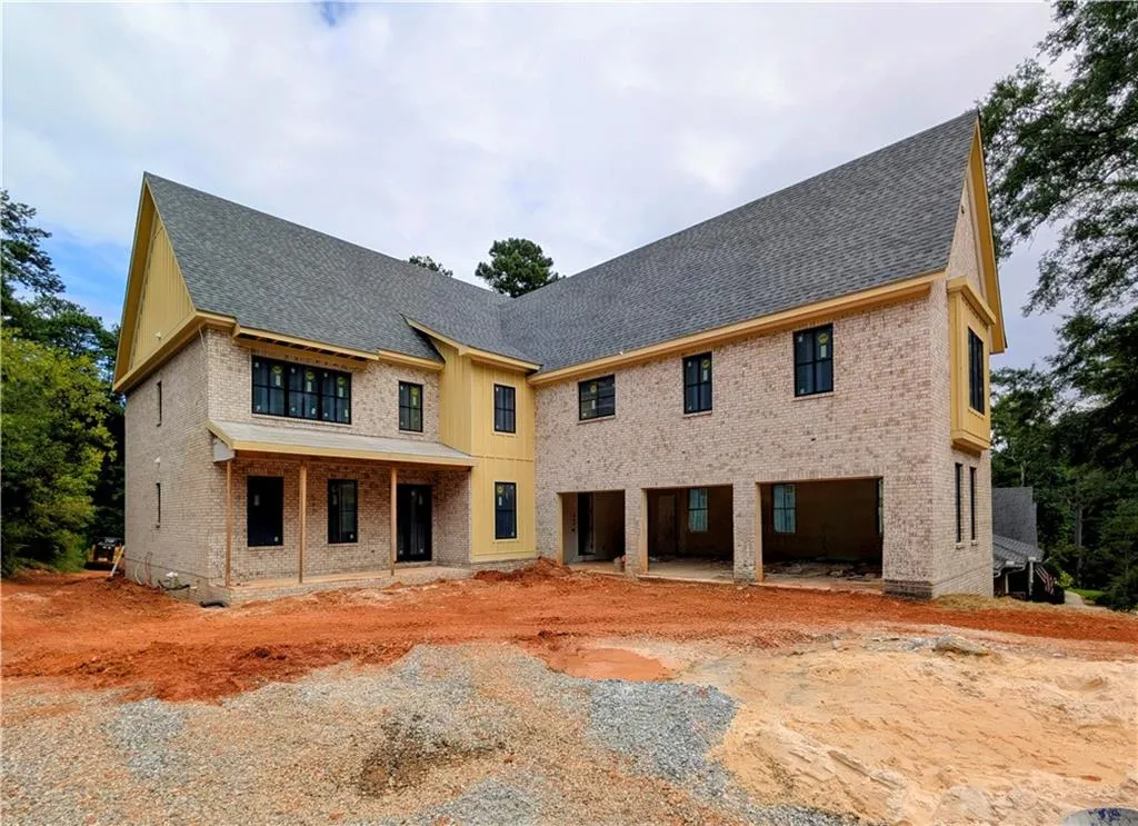 Back of house featuring a shingled roof, brick siding, and a patio area