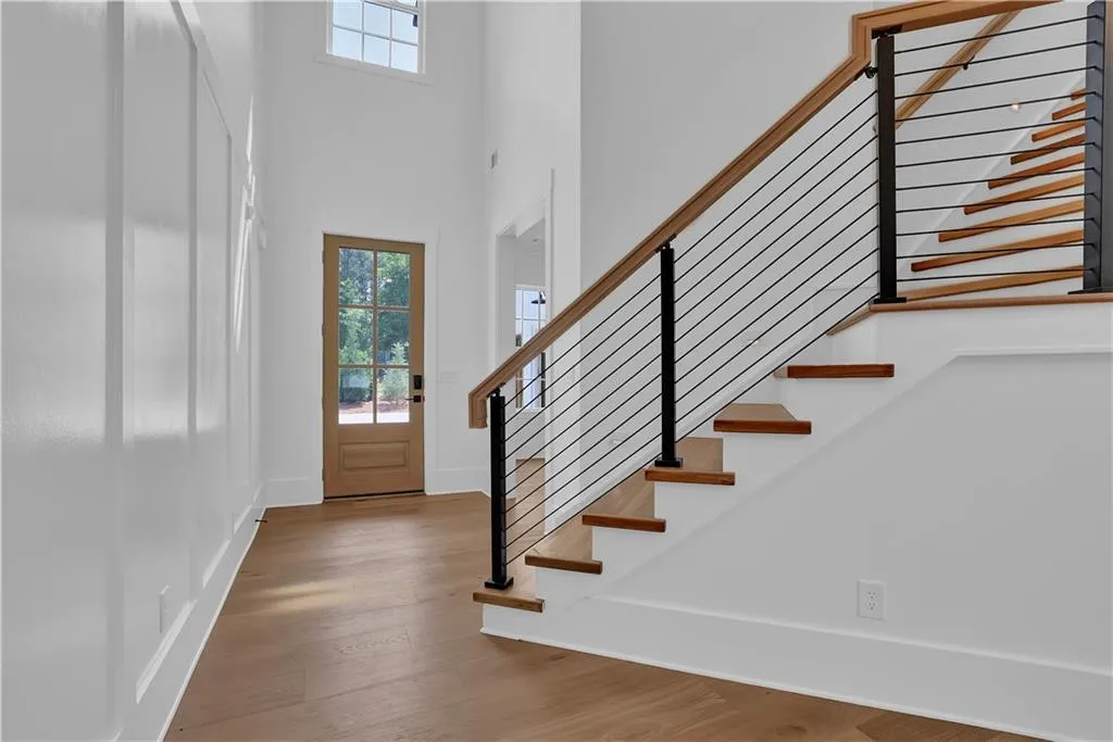 Entryway featuring plenty of natural light, wood finished floors, a high ceiling, and stairs