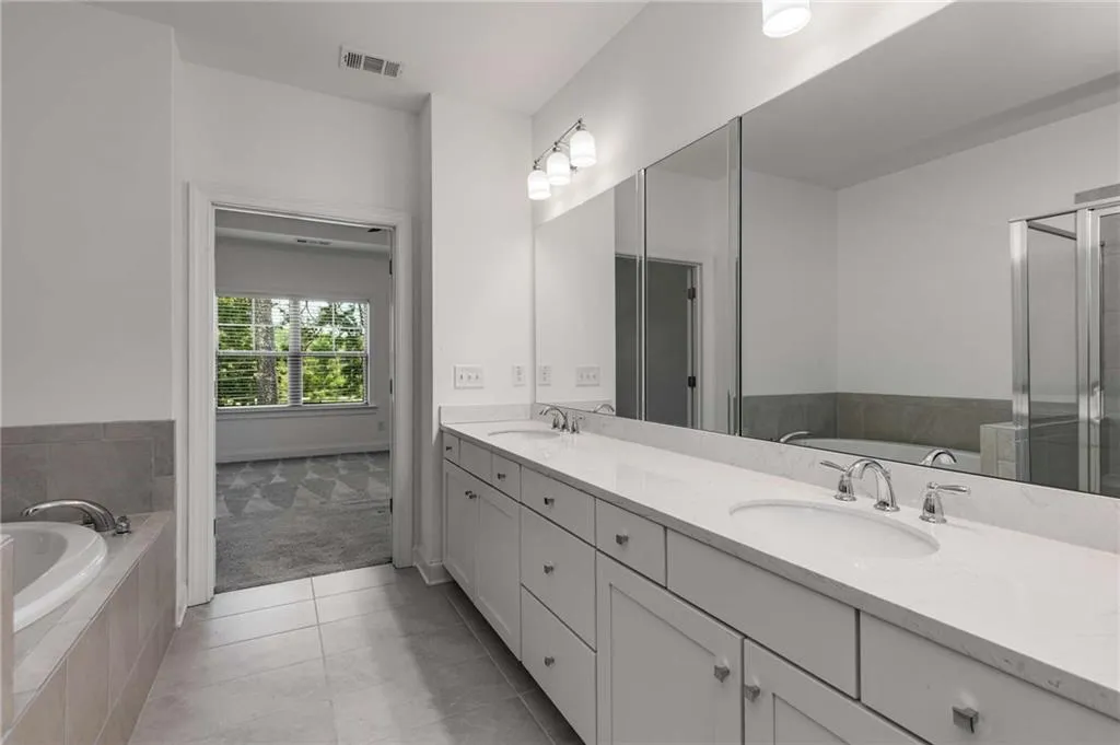 Bathroom featuring a bath, double vanity, tile patterned flooring, and a stall shower