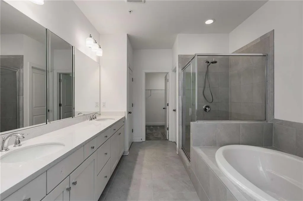 Bathroom featuring a shower stall, a garden tub, double vanity, and recessed lighting