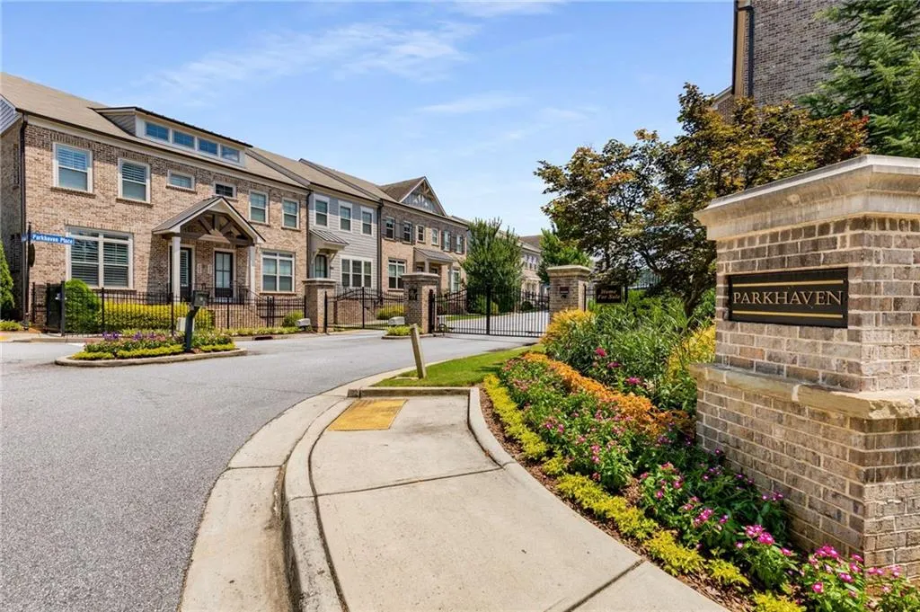 View of asphalt street with a residential view, a gate, curbs, sidewalks, and a gated entry