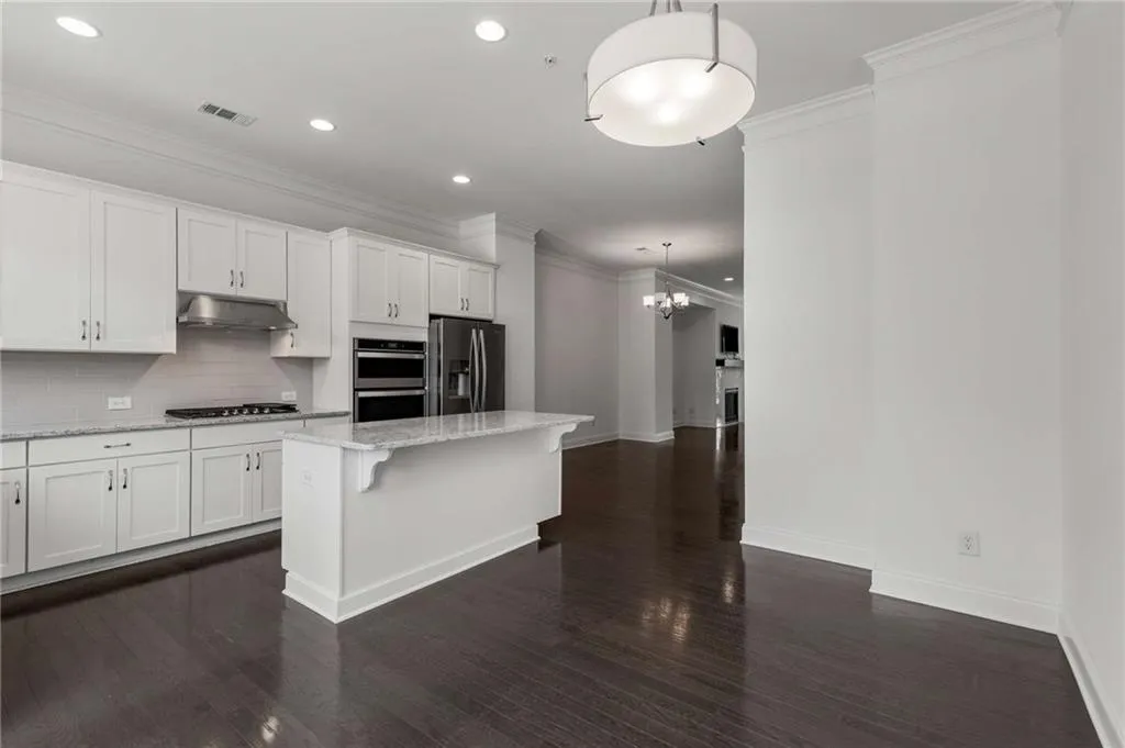 Kitchen featuring stainless steel appliances, crown molding, a center island, decorative backsplash, and white cabinets