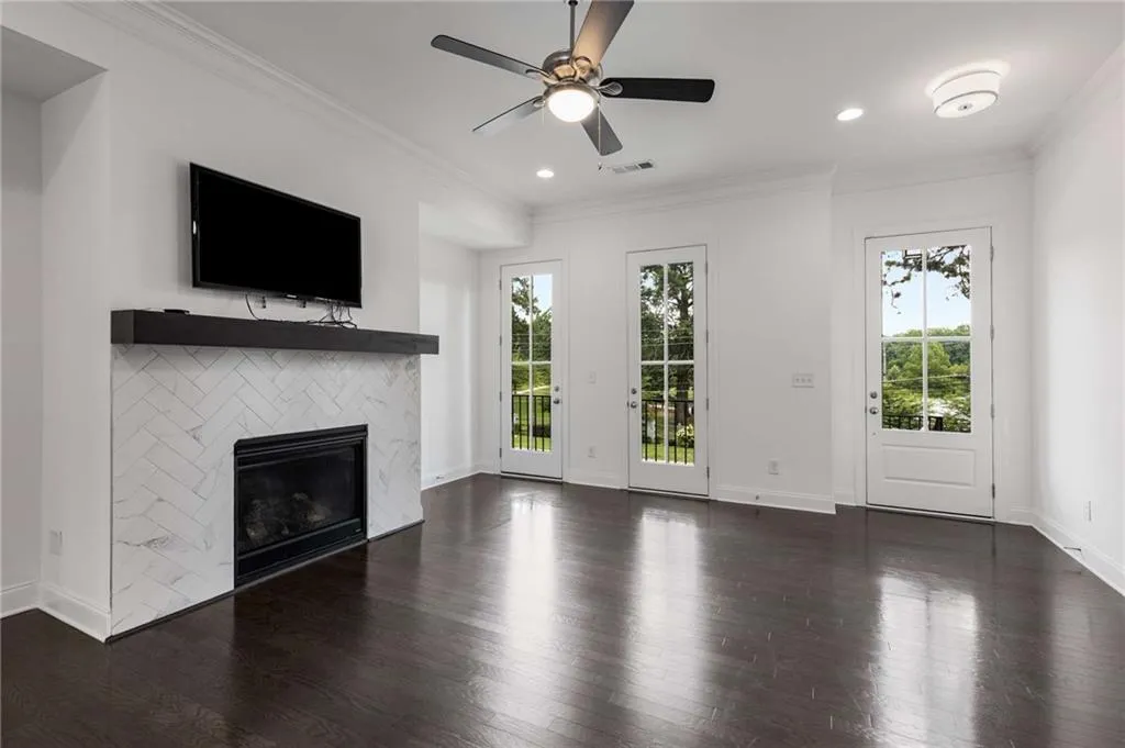 Unfurnished living room with dark wood-type flooring, a tiled fireplace, ceiling fan, crown molding, and recessed lighting