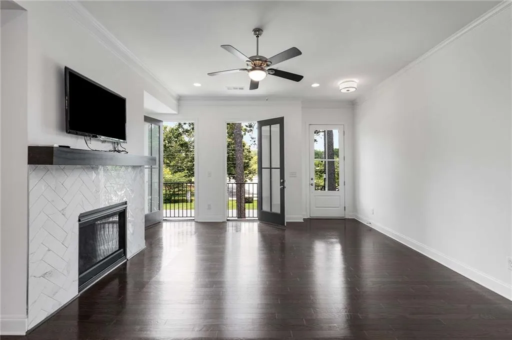 Unfurnished living room featuring wood finished floors, a ceiling fan, a tile fireplace, ornamental molding, and recessed lighting