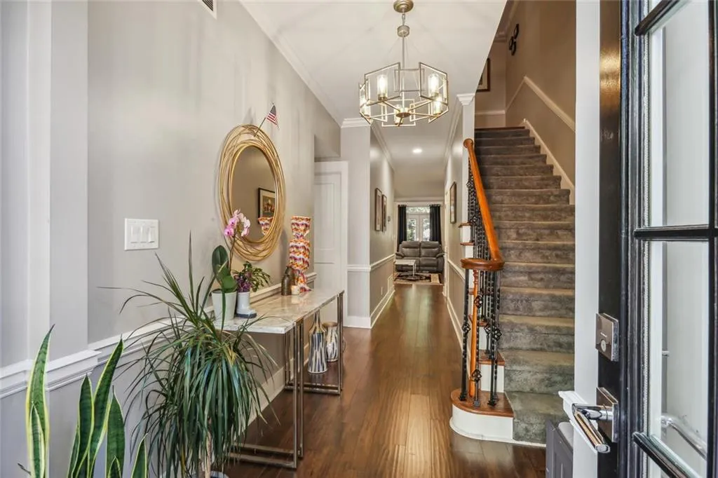 Foyer entrance featuring crown molding, dark wood-type flooring, and a notable chandelier