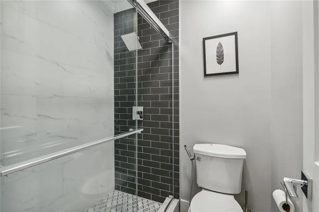 Bathroom featuring tiled shower and toilet