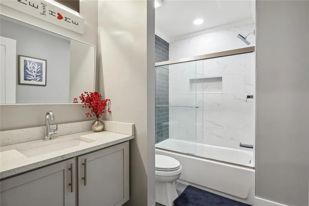 Full bathroom featuring toilet, vanity, and shower / bath combination with glass door