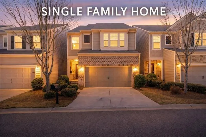 Two-story residential exterior featuring a combination of brick and siding, an attached two-car garage, concrete driveway, and established front landscaping