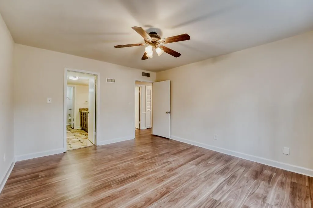 Master bedroom featuring light wood-style flooring, ceiling fan, and connected bathroom