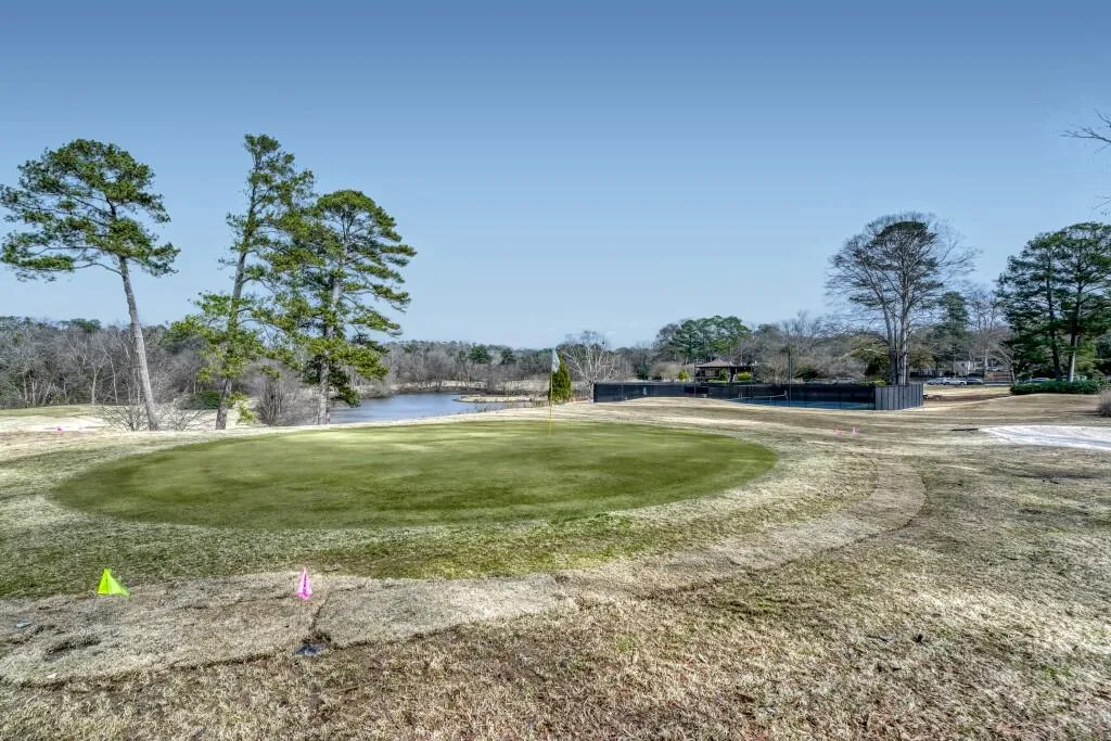 Surrounding community with golf course view, a lawn, view of wooded area, and a water view