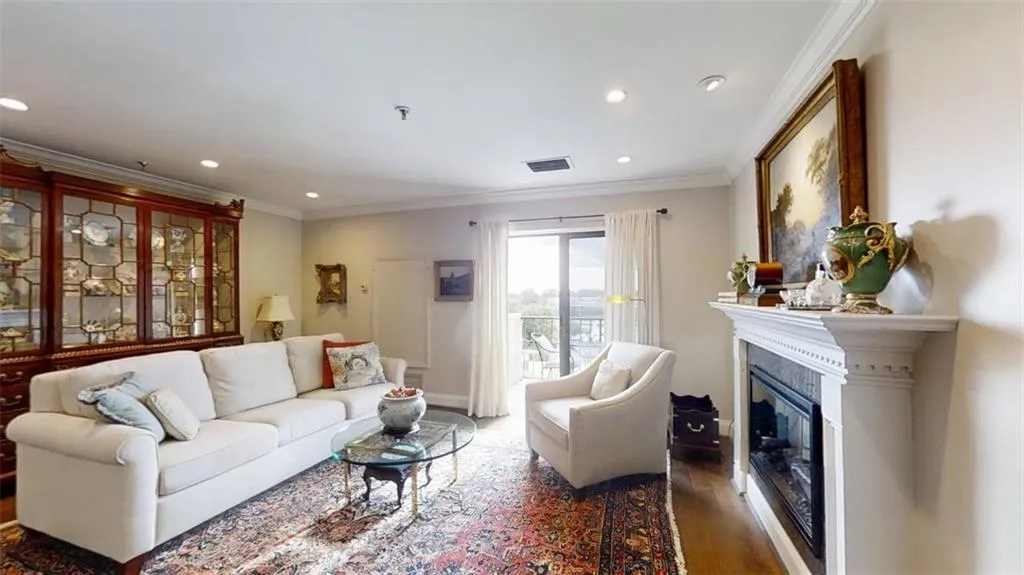 Living room featuring recessed lighting, ornamental molding, wood finished floors, and a glass covered fireplace