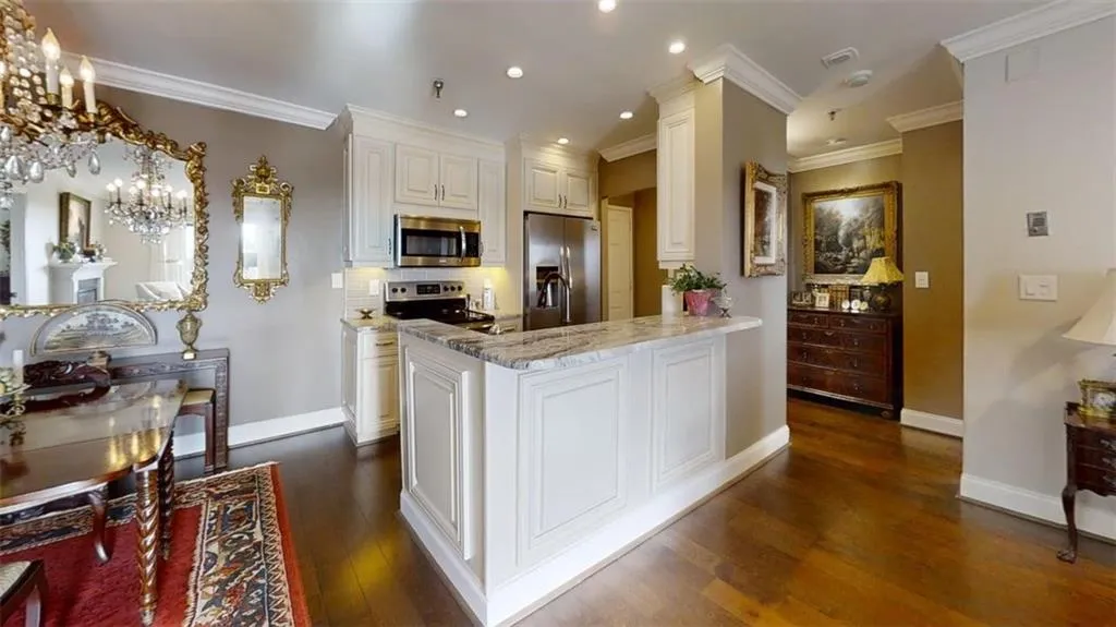 Kitchen with stainless steel appliances, dark wood-type flooring, light stone countertops, recessed lighting, and backsplash