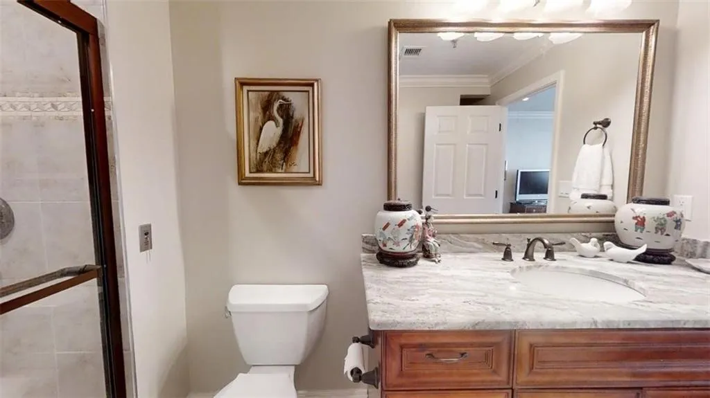 Bathroom with vanity, crown molding, and a tile shower