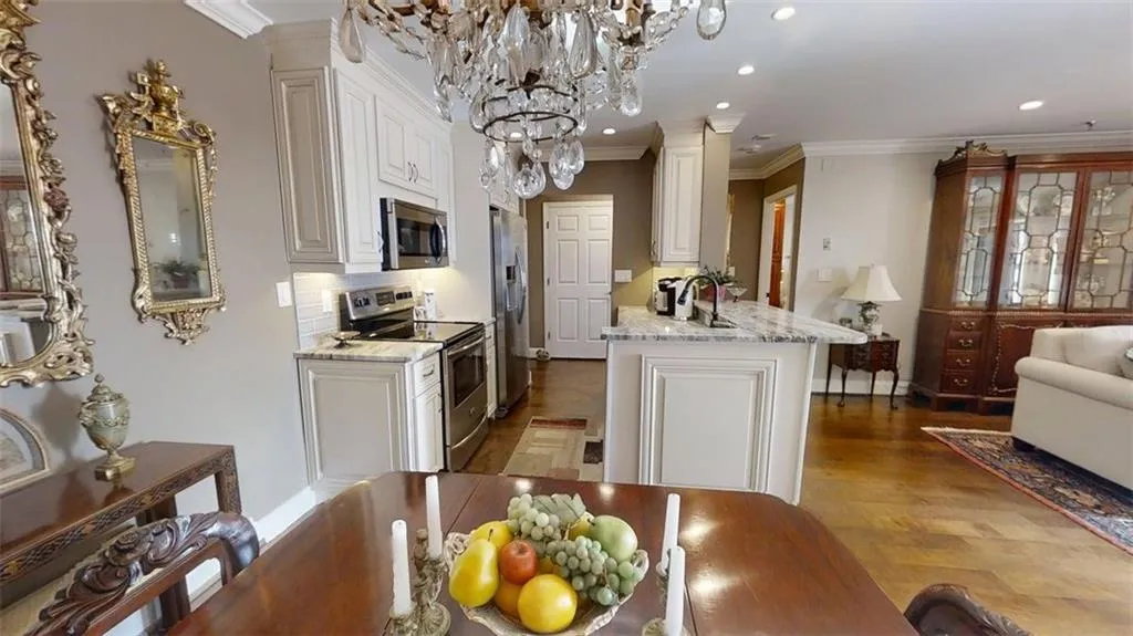 Kitchen featuring stainless steel appliances, recessed lighting, white cabinets, ornamental molding, and decorative columns