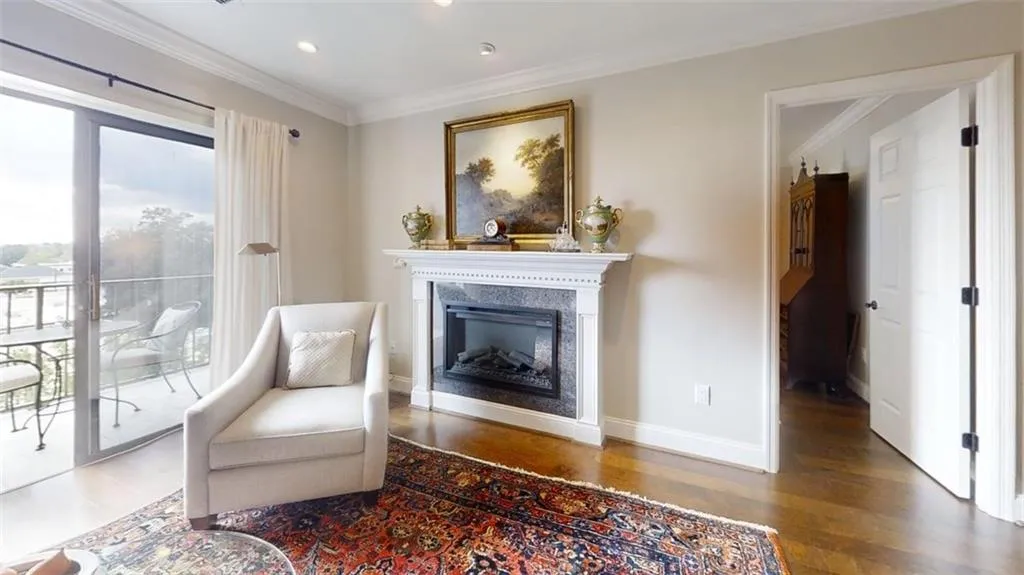 Sitting room with wood finished floors, ornamental molding, a glass covered fireplace, and recessed lighting