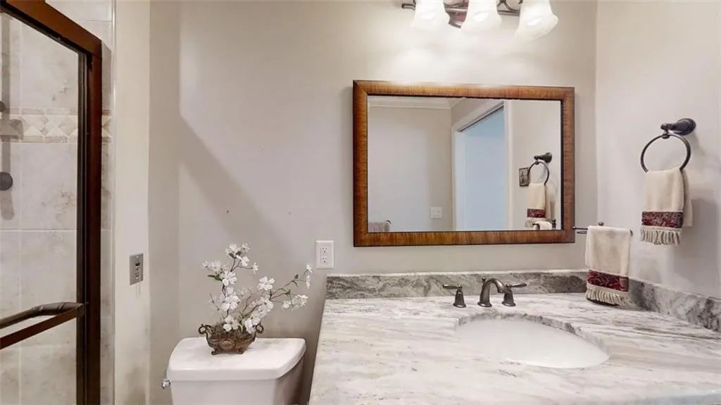 Bathroom featuring vanity, a tile shower, and a chandelier
